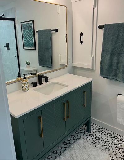 Double-sink vanity with new faucets, mirrors, and wall sconces in a primary bathroom renovation.