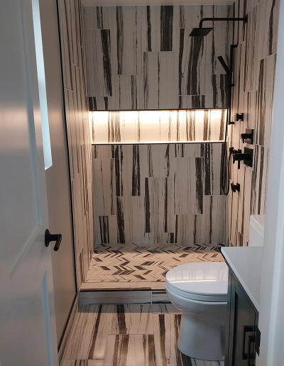 Bright bathroom featuring white subway tile, black fixtures, and a custom shower niche.
