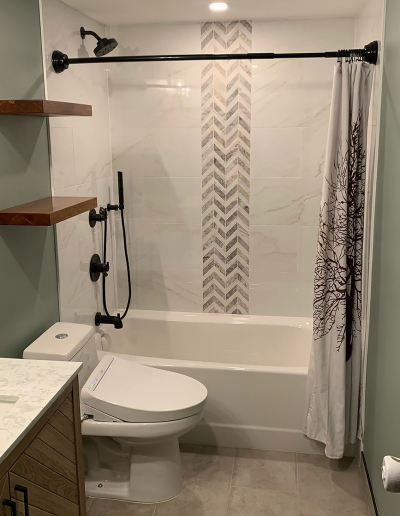 Bright bathroom featuring white subway tile, black fixtures, and a custom shower niche.