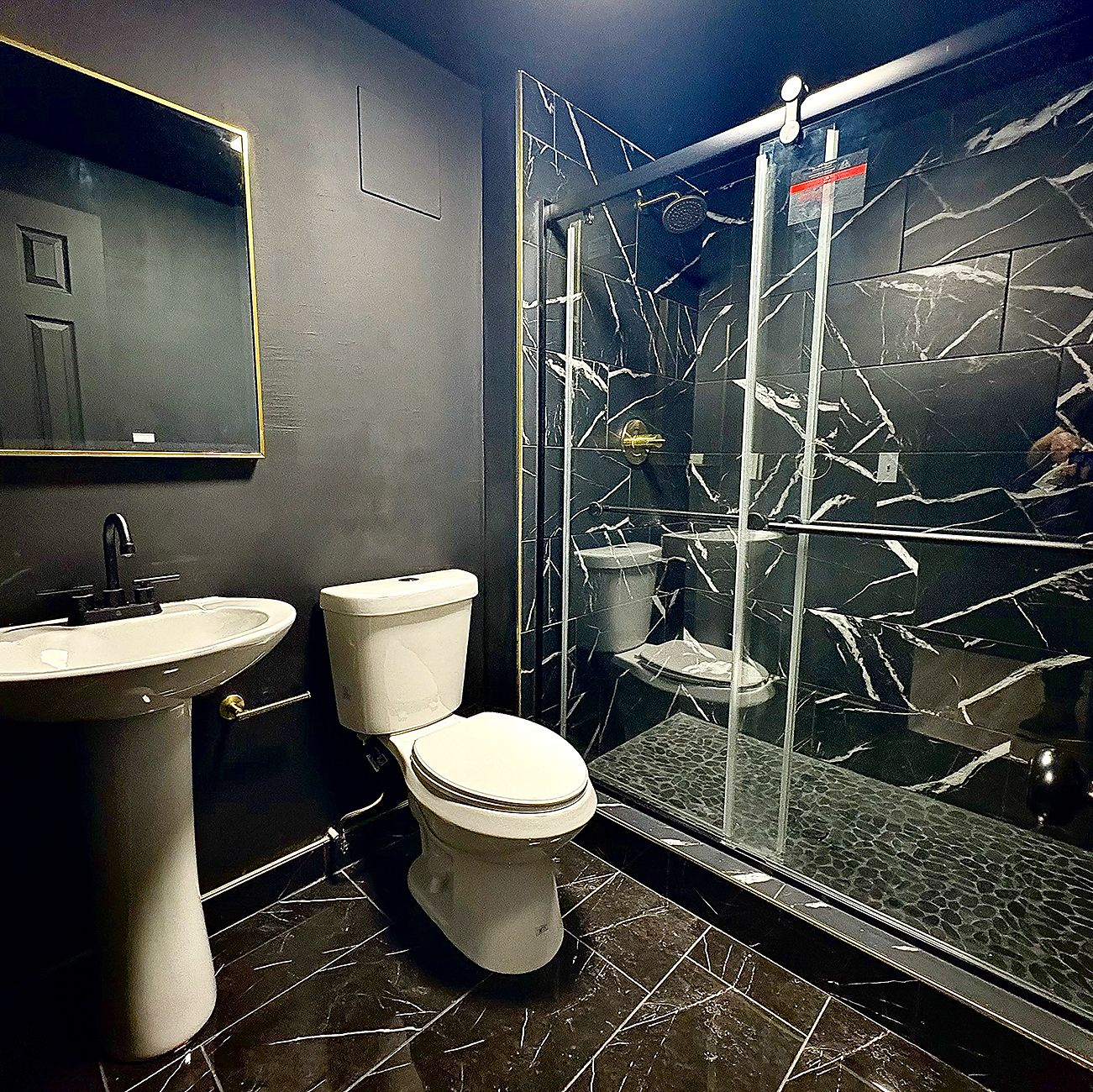 Walk-in shower with frameless glass, floor tile, and built-in bench in a Denver area remodel.